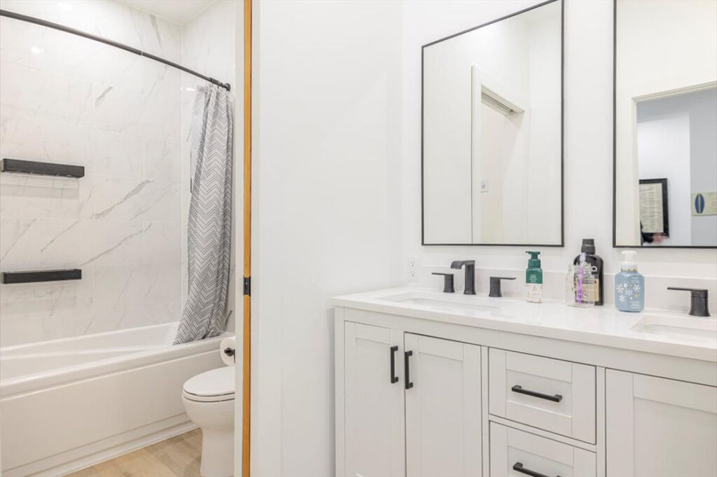 basement double sink vanity with sliding door to toilet with jetted tub/shower